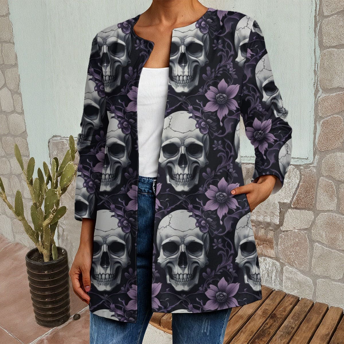 Person wearing a long-sleeve shirt with skull and floral pattern in front of a stone wall.